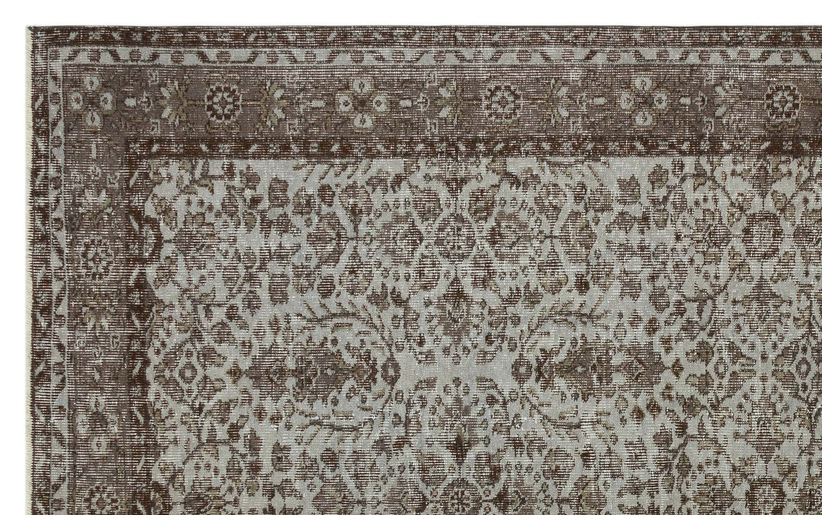 Brown and light gray traditional rug with a distressed floral medallion pattern and a decorative border.