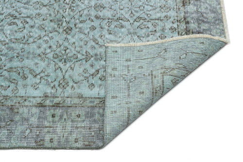 Load image 1 in gallery view. Light blue and grey distressed rug with a traditional floral medallion pattern, shown with a corner folded over.