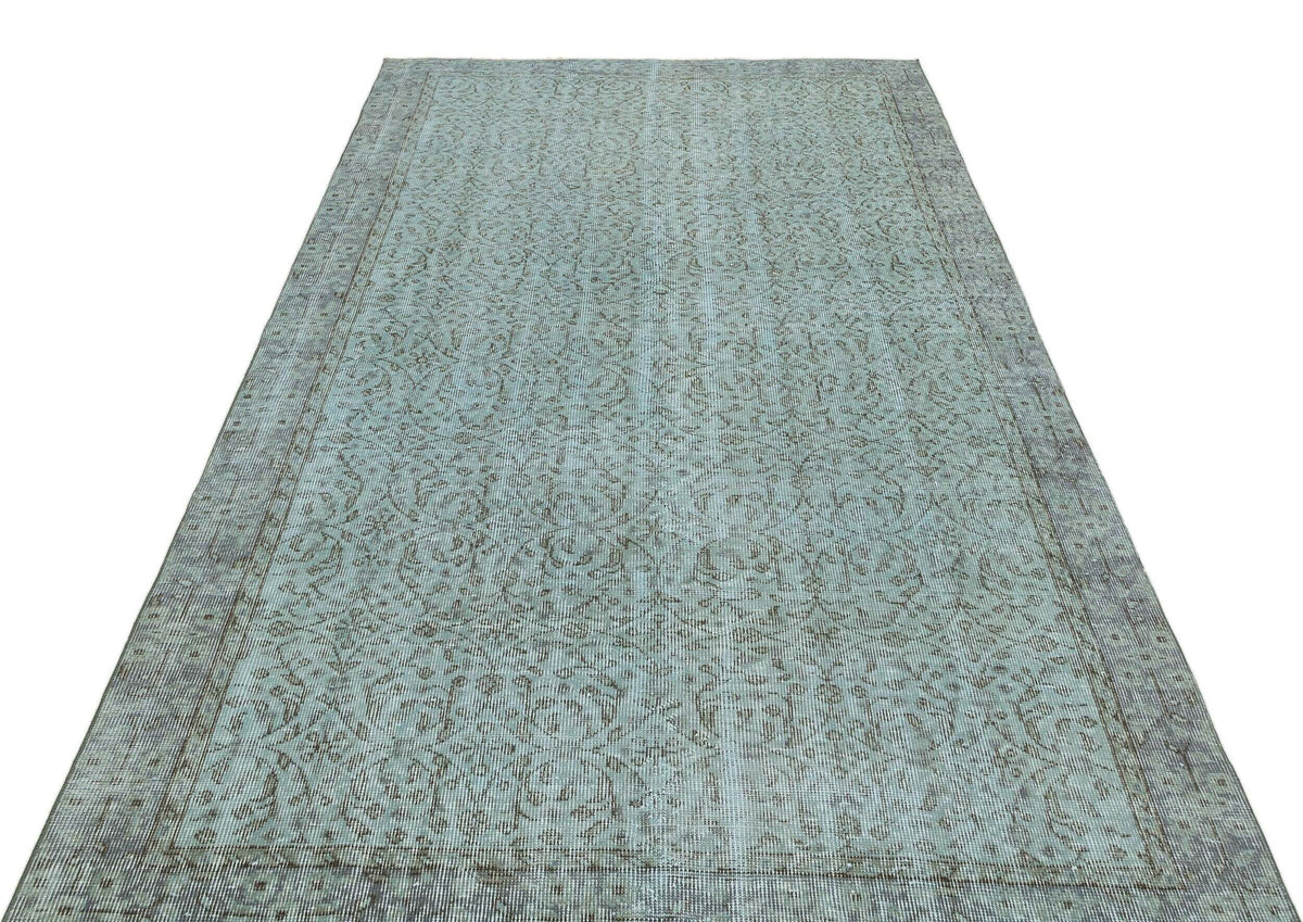 Light blue and grey distressed rug with an intricate floral medallion pattern and a wide decorative border.