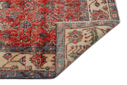 Load image 1 in gallery view. Red, blue, and beige traditional rug with a floral medallion pattern and a folded corner showing the underside.