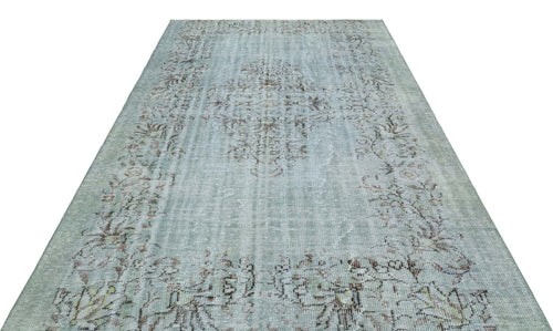 Load image 1 in gallery view. Distressed sage green rug with a faded brown central medallion and floral border on a white background.