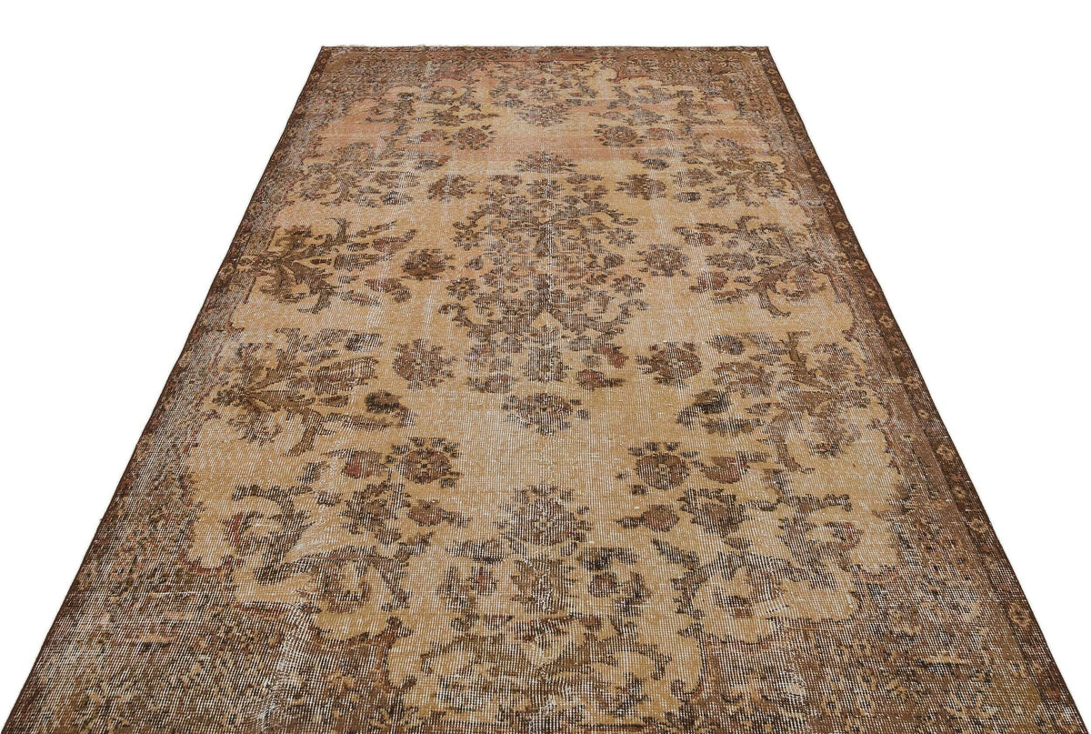 Distressed tan and brown vintage-style rug with a central floral medallion and ornate border.