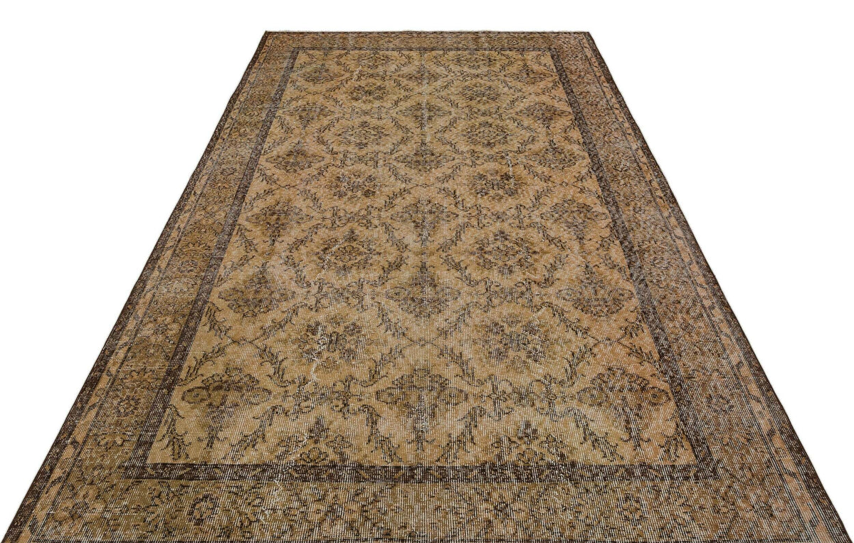Tan and brown vintage-style rug with a distressed floral medallion pattern and a wide decorative border.