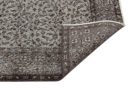 Load image 1 in gallery view. Brown and beige vintage-style rug with a traditional floral medallion pattern, shown with a corner folded over.