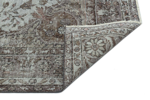Load image 1 in gallery view. Brown and grey distressed traditional rug with a floral medallion pattern, shown with a corner folded over.