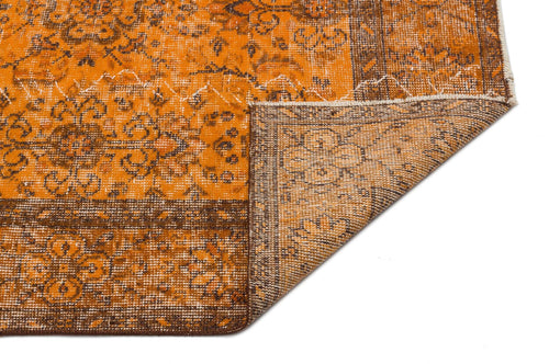 Load image 1 in gallery view. Distressed orange and brown rug with a traditional floral medallion pattern, shown with a corner folded over.