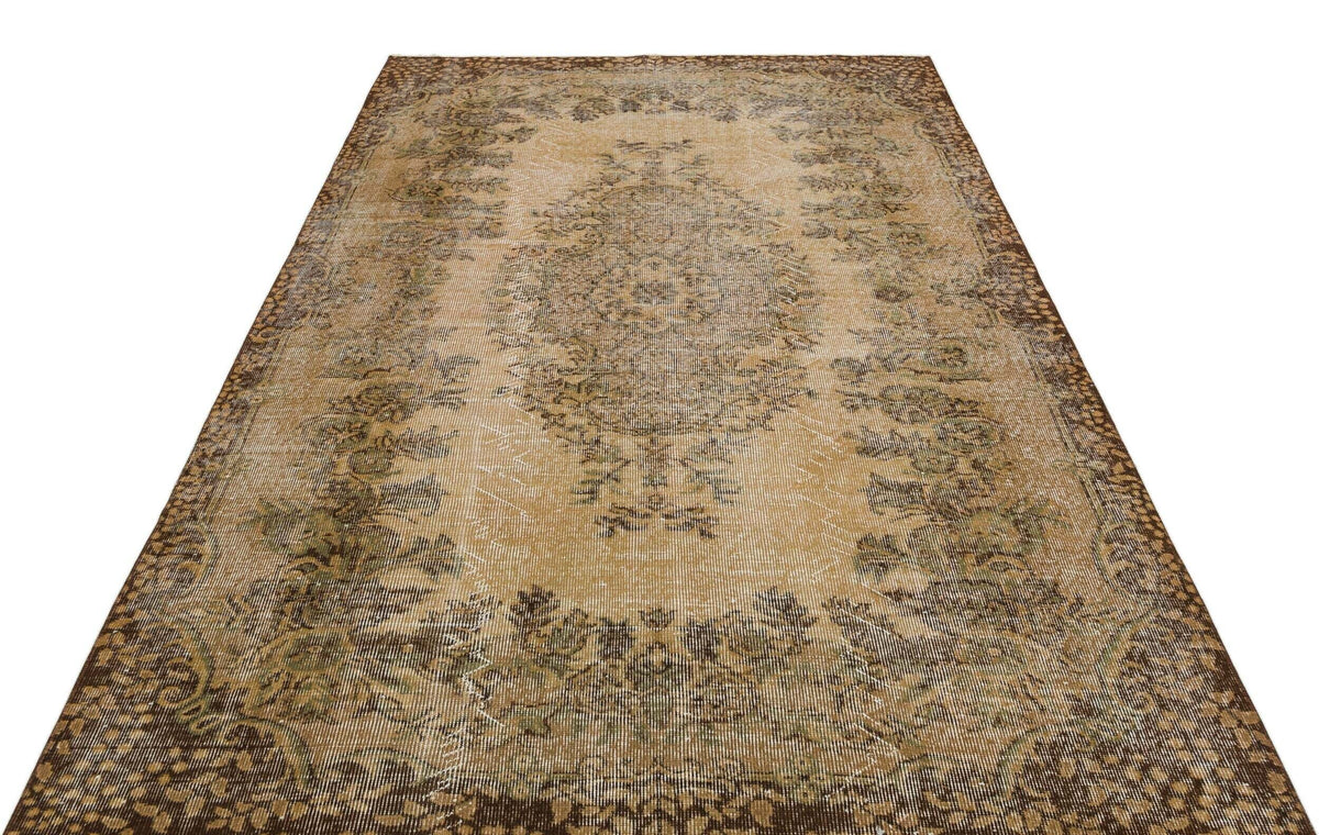 Distressed tan and brown vintage-style rug with a central floral medallion and ornate border on a white background.