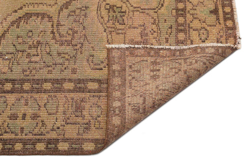 Load image 1 in gallery view. Tan and brown vintage-style rug with a traditional geometric border and floral motifs, showing a folded corner.