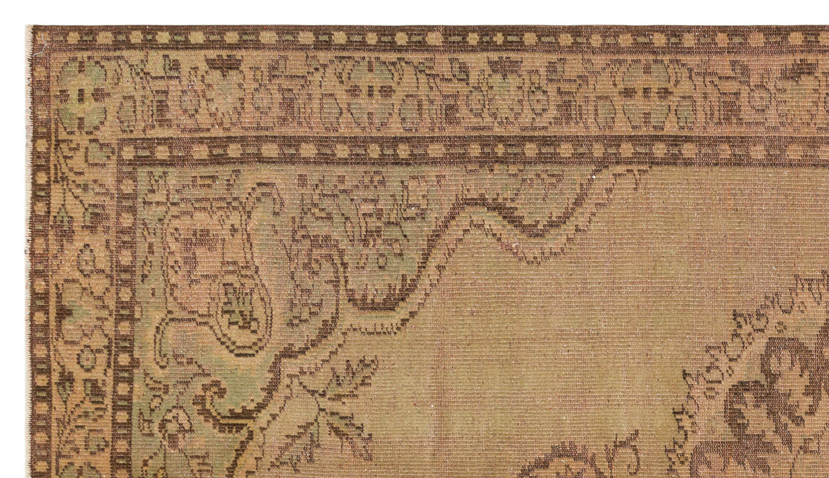 Tan and sage green vintage-style rug with a distressed traditional floral border and central medallion pattern.