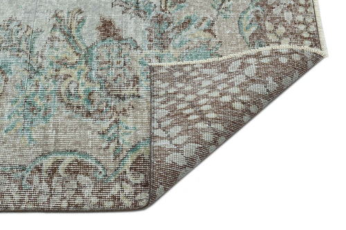 Load image 1 in gallery view. Distressed beige, brown, and teal floral medallion rug with a corner folded over to reveal the woven backing.