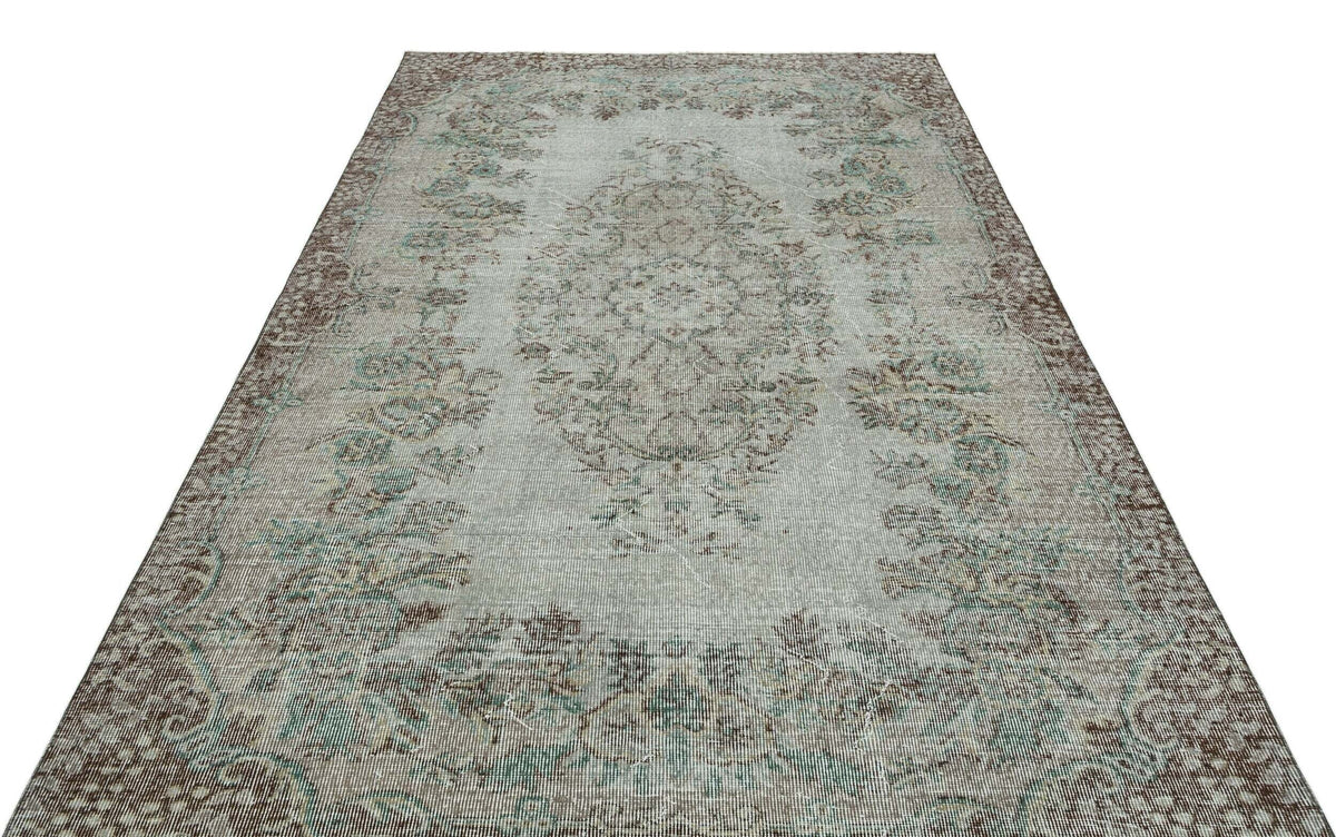 Distressed light blue and brown vintage-style rug with a central floral medallion and ornate border.