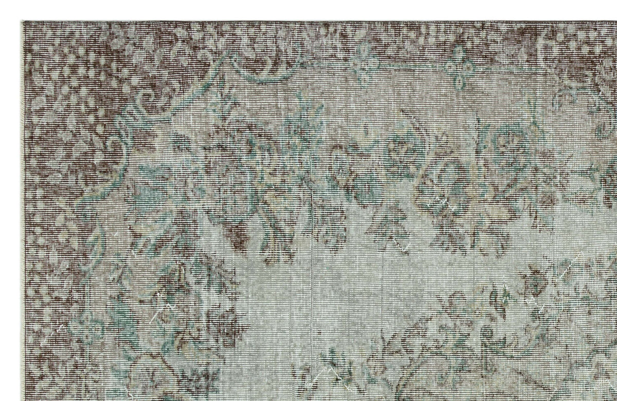 Distressed vintage-style rug with a faded floral medallion pattern in shades of brown, sage green, and cream.