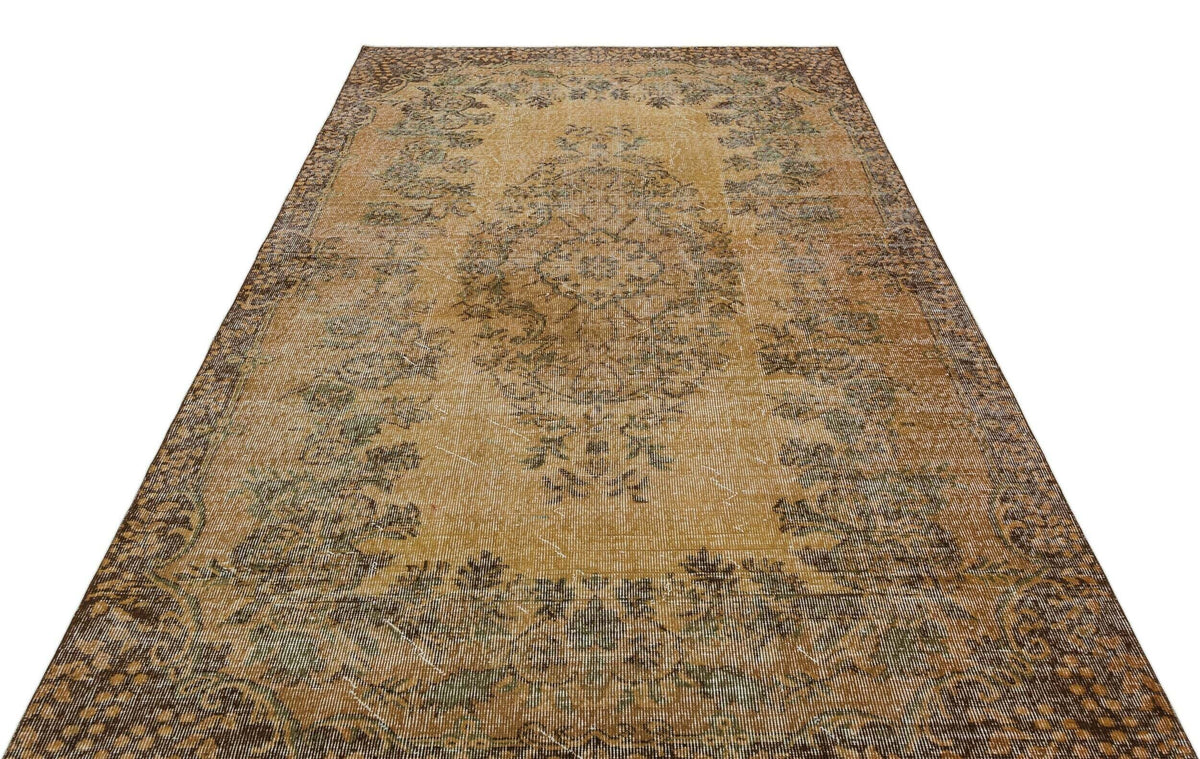 Distressed ochre and brown vintage-style rug with a central floral medallion and ornate border on a white background.