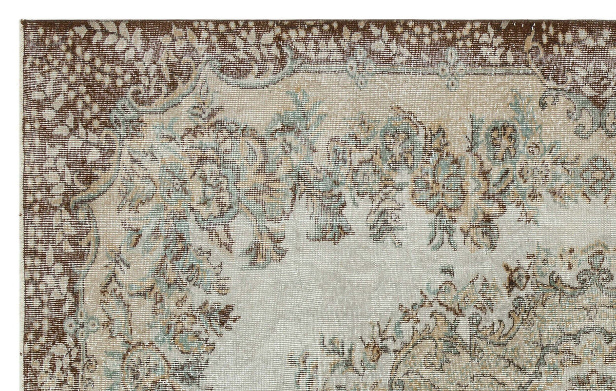 Distressed beige, brown, and sage green rug with a traditional floral medallion pattern and a wide decorative border.