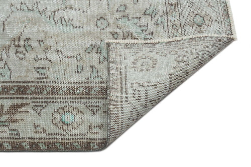 Load image 1 in gallery view. Distressed sage green and beige rug with a traditional medallion pattern, shown with a corner folded over.