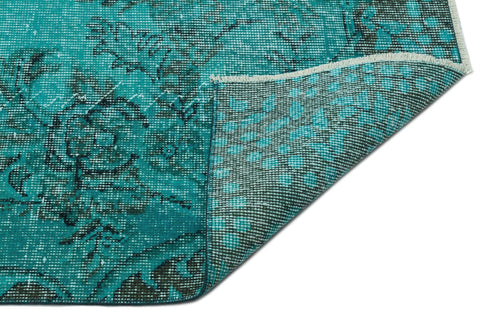 Load image 1 in gallery view. Teal and black distressed floral rug with a corner folded over to reveal the woven backing on a white background.