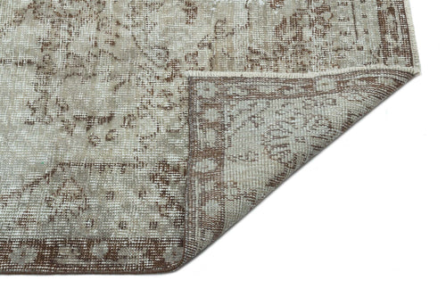 Load image 1 in gallery view. Beige and brown distressed traditional rug with a floral medallion pattern, shown with a corner folded over.