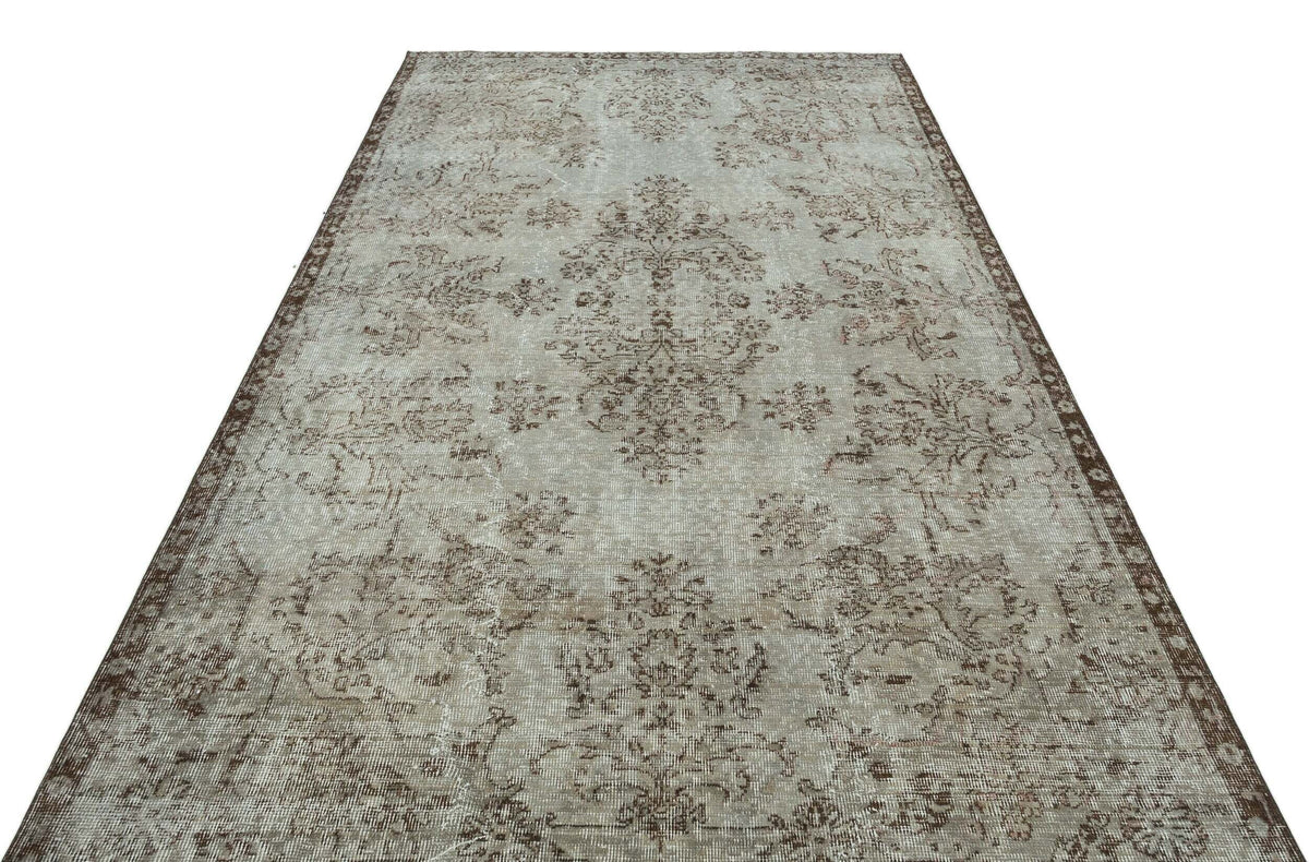 Light gray and brown distressed vintage-style rug with a central floral medallion and ornate border.