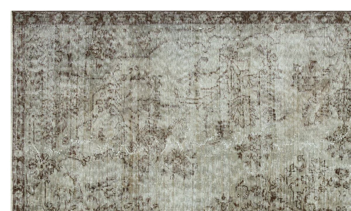 Taupe and brown distressed rug with a faded traditional floral medallion pattern.