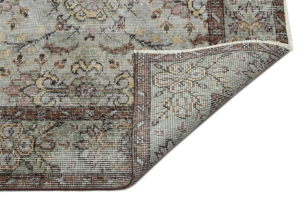 Sage green, brown, and cream traditional floral medallion rug with a corner folded over to show the underside.