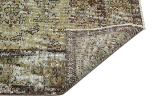 Load image 1 in gallery view. Distressed beige and brown rug with a traditional floral medallion pattern, shown with a corner folded over.