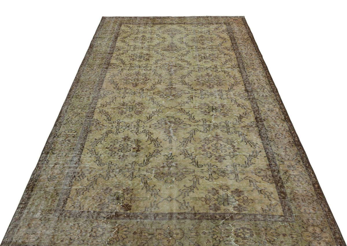 Distressed olive and brown vintage rug with a faded floral medallion pattern and a wide decorative border.