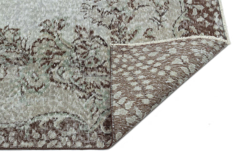Load image 1 in gallery view. Grey and brown distressed floral medallion rug with a corner folded over to show the woven backing.