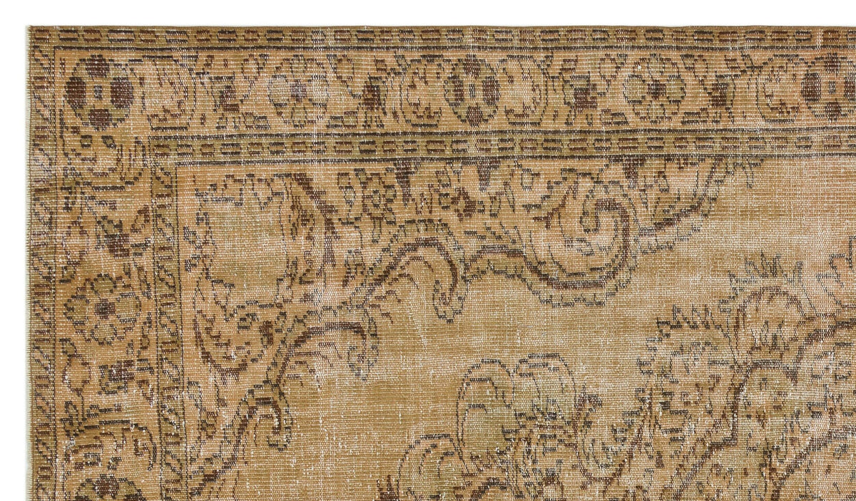 Tan and brown vintage-style rug with a distressed floral medallion border and ornate scrollwork pattern.
