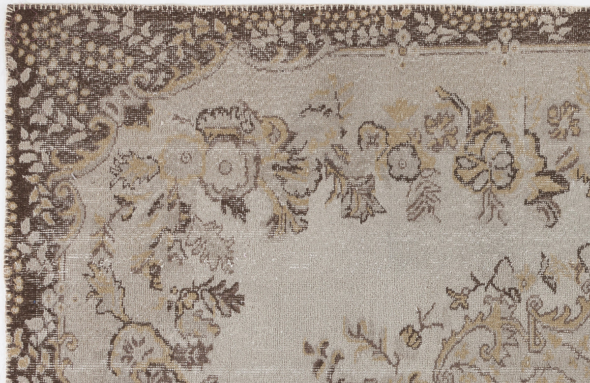 Taupe and brown distressed rug with a traditional floral medallion pattern and a decorative border.