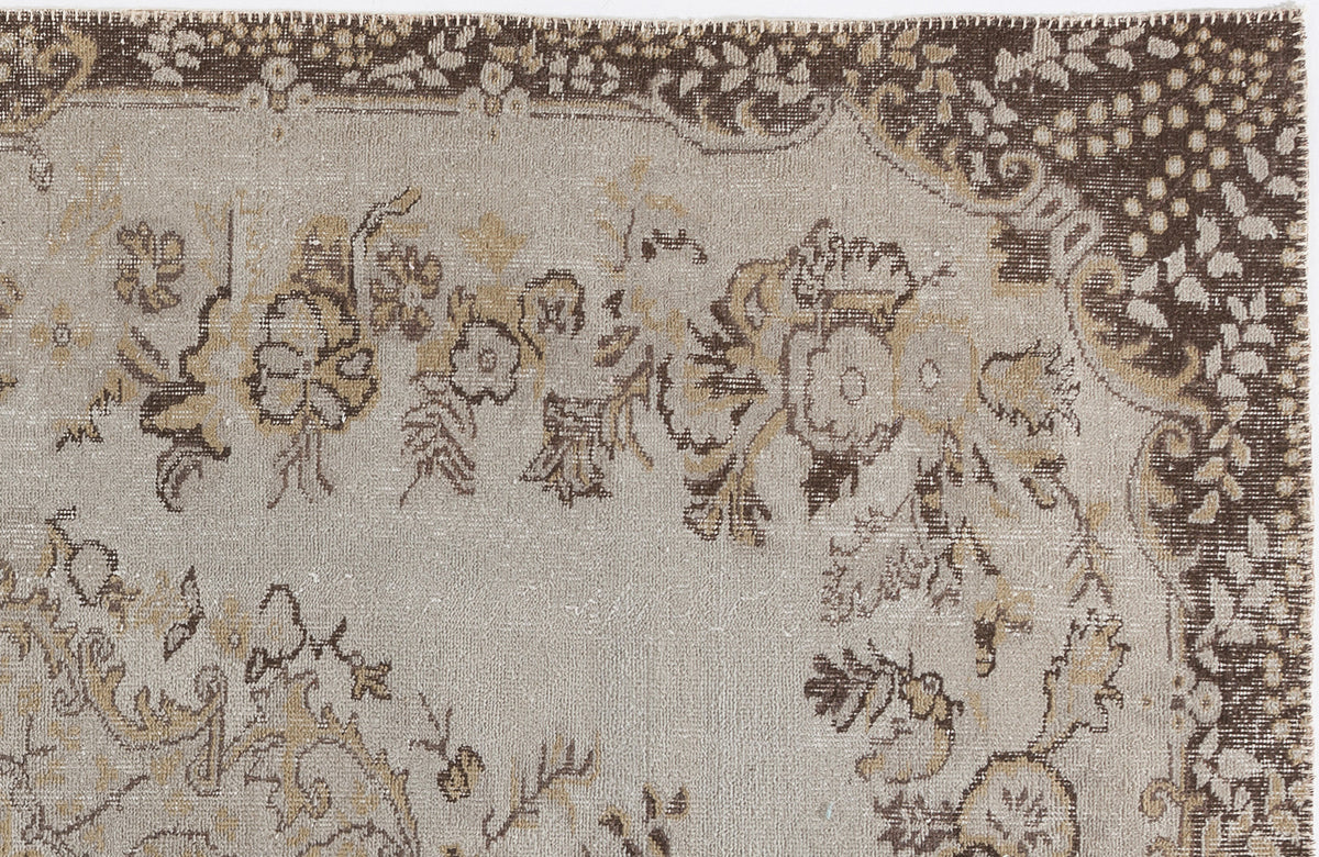 Beige and brown vintage-style rug with a distressed floral medallion pattern and a dark decorative border.