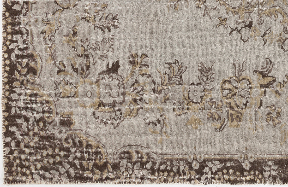 Taupe and brown distressed rug with a traditional floral medallion pattern and a wide decorative border.