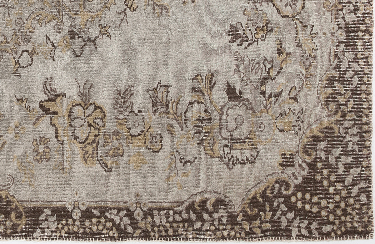 Taupe and brown rug with a distressed floral medallion pattern and a detailed decorative border.