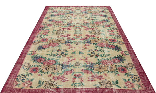 Load image 1 in gallery view. Beige vintage-style rug with a distressed floral pattern in red, blue, and green, featuring a wide red border.