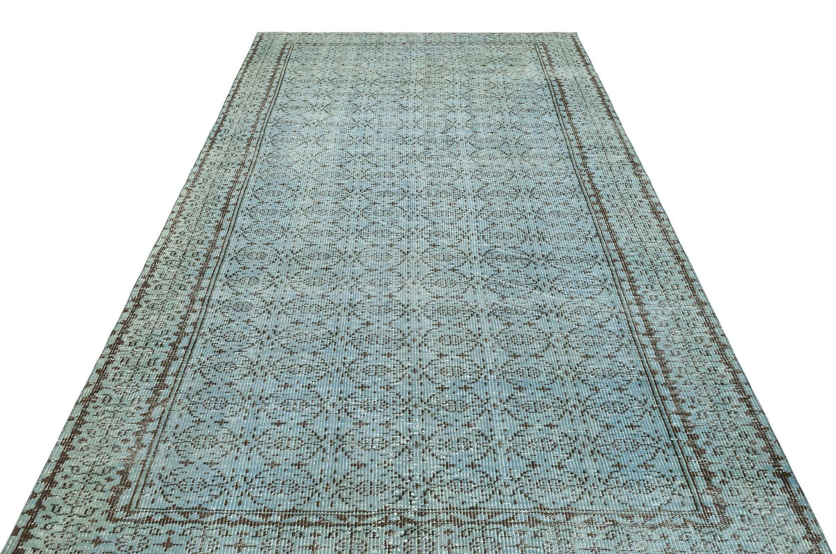 Light blue and brown distressed runner rug with a repeating geometric medallion pattern and a bordered edge.