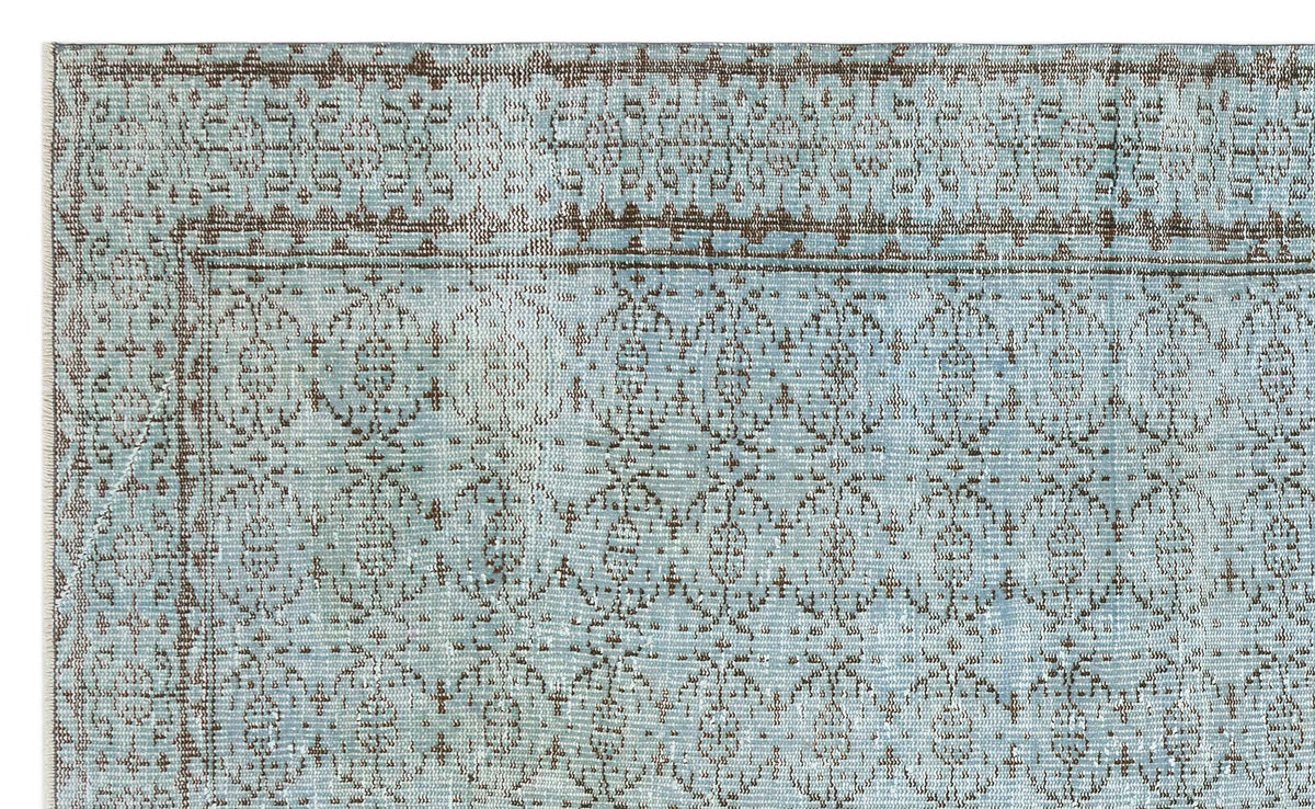 Light blue and brown distressed rug with a traditional repeating medallion pattern and a bordered edge.