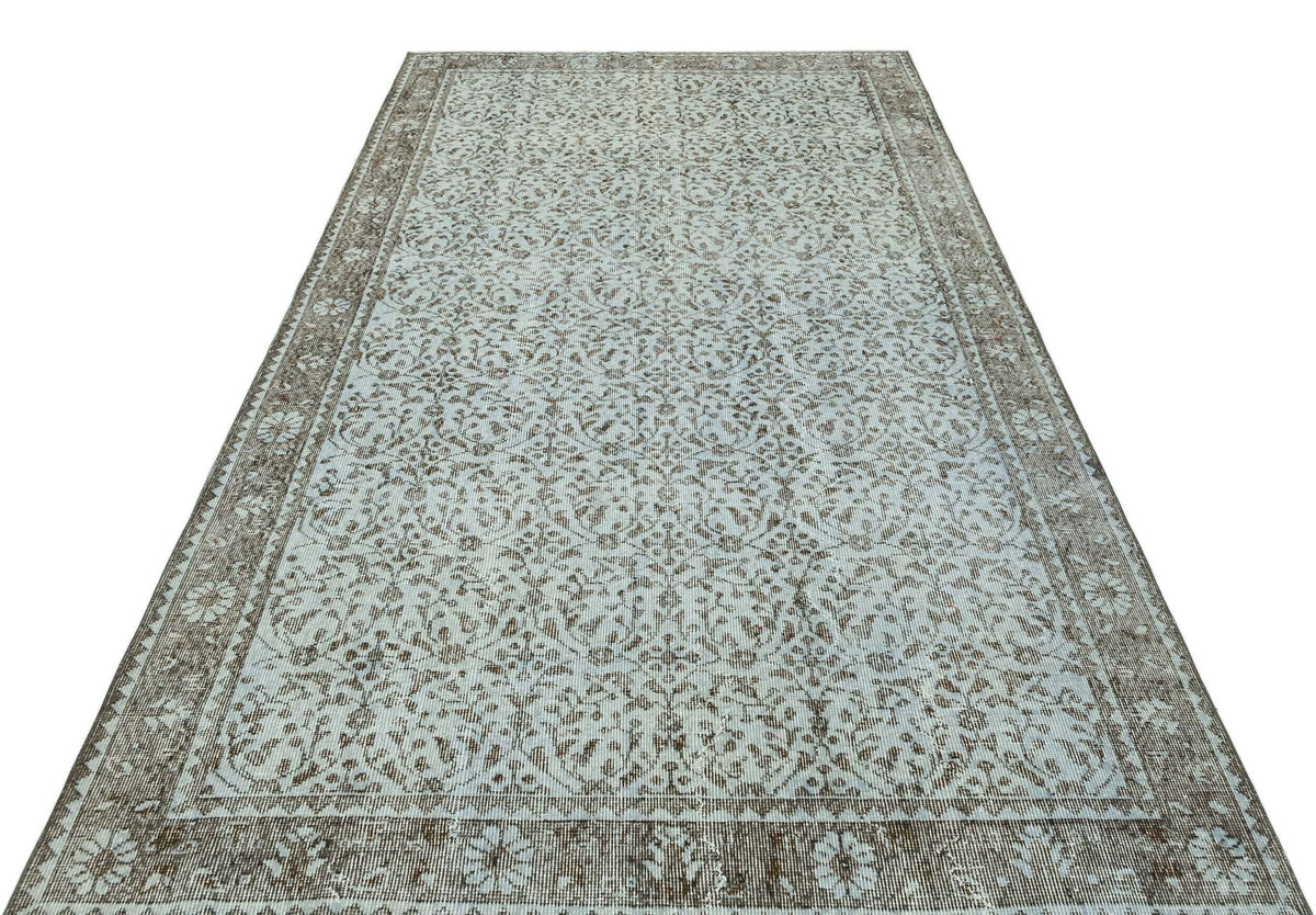 Light blue and brown vintage-style rug with an intricate floral medallion pattern and a wide decorative border.