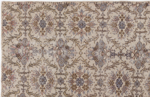 Load image 1 in gallery view. Beige rug with a distressed, repeating floral medallion pattern in muted tones of slate blue, brown, and soft pink.