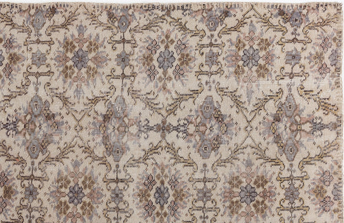 Load image 1 in gallery view. Beige rug with a distressed, repeating floral medallion pattern in muted brown, grey, and dusty rose tones.