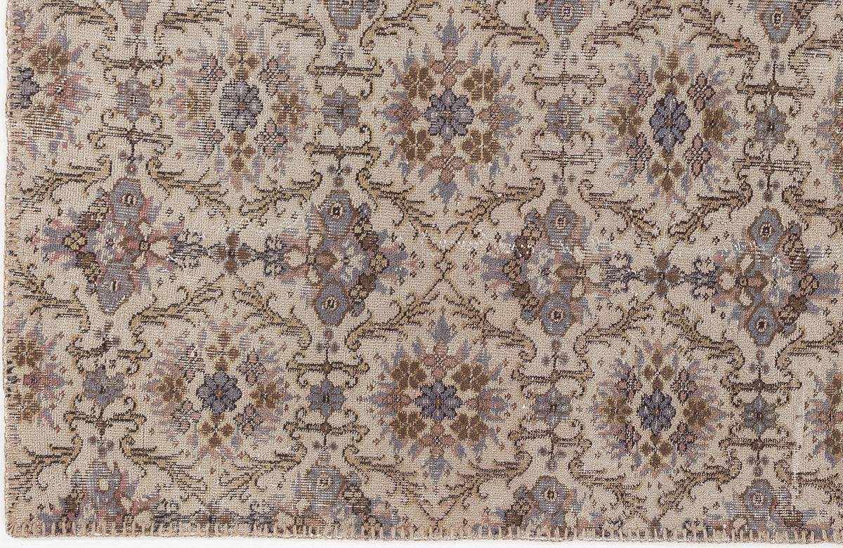 Beige rug with a repeating floral medallion pattern in muted tones of slate blue, brown, and dusty rose.