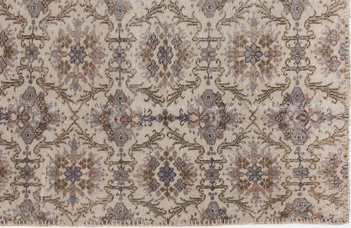 Load image 1 in gallery view. Beige rug with a distressed, repeating floral medallion pattern in muted tones of brown, grey, and mauve.