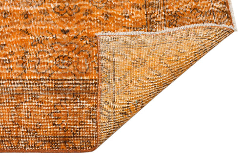 Load image 1 in gallery view. Burnt orange and brown distressed rug with a traditional floral medallion pattern, shown with a folded corner.