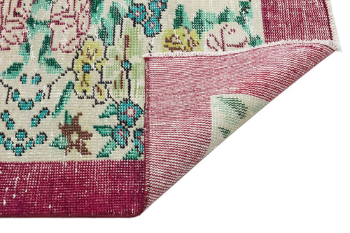 Load image 1 in gallery view. Cream rug with floral pattern in teal, yellow, and magenta, featuring a folded corner revealing the woven backing.