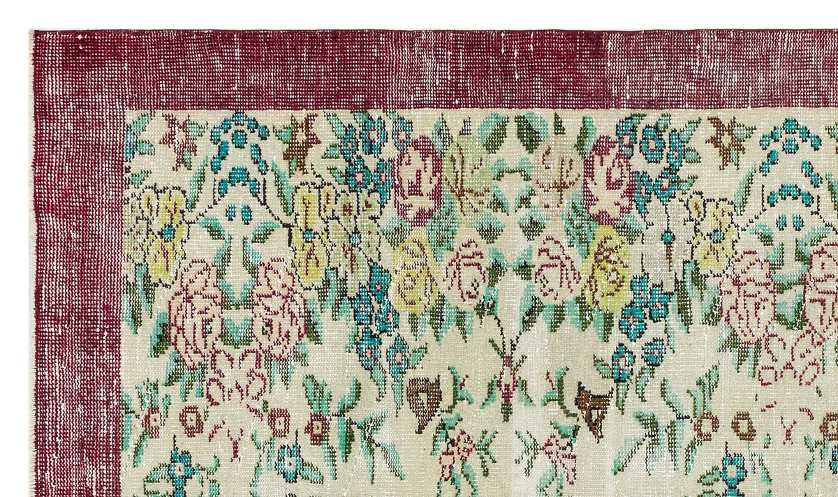 Distressed cream rug with a deep red border and a multicolored floral pattern in teal, yellow, and pink.