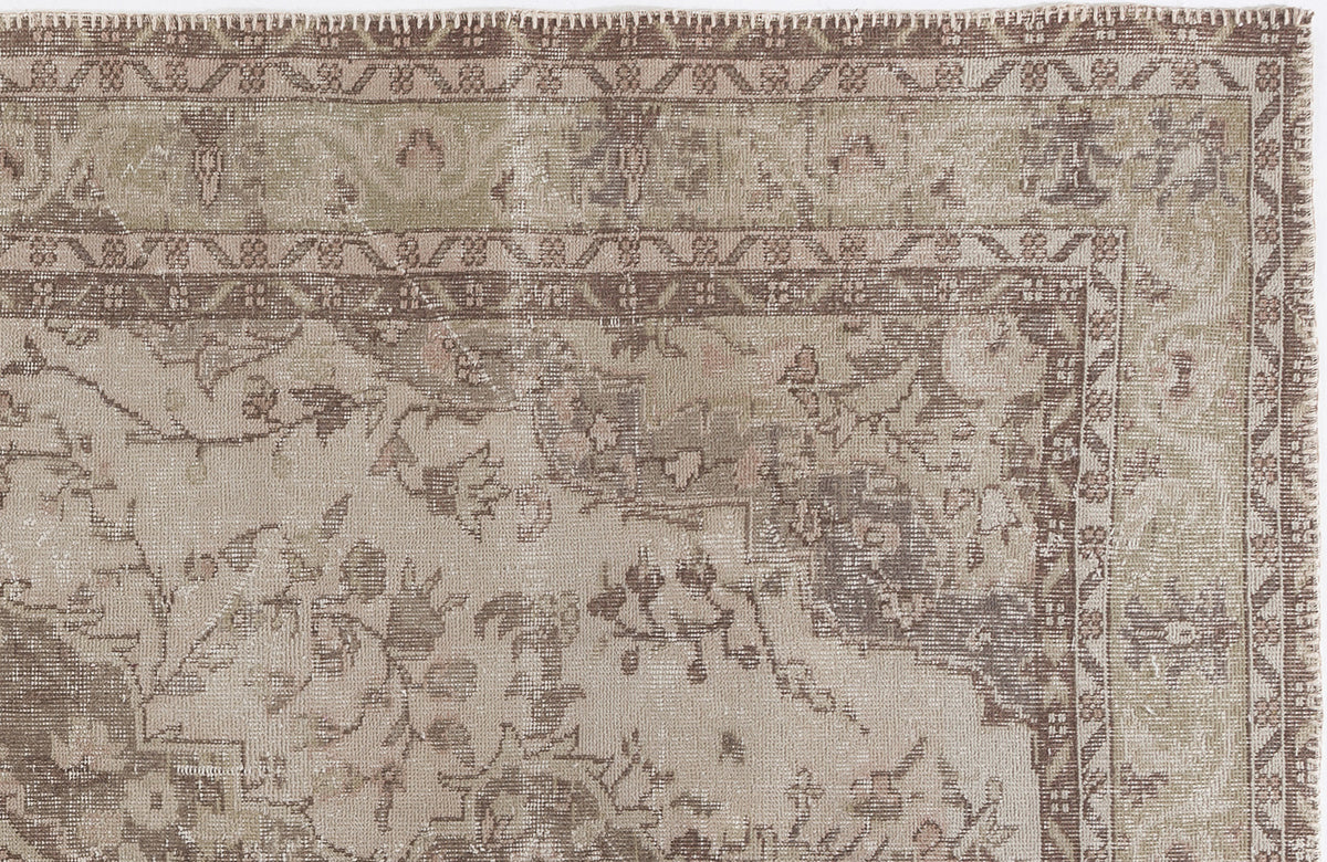 Distressed beige and brown rug with a traditional floral medallion pattern and geometric border.