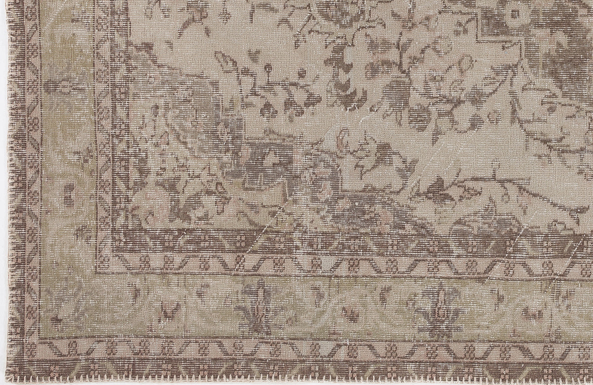 Taupe and beige distressed traditional rug with a faded floral medallion pattern and a geometric border.