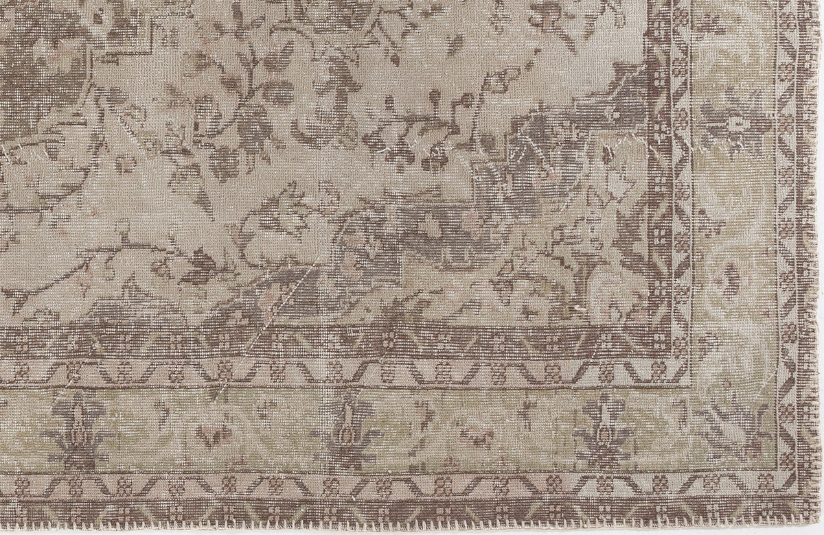 Taupe and beige distressed rug with a traditional floral medallion pattern and a geometric border.