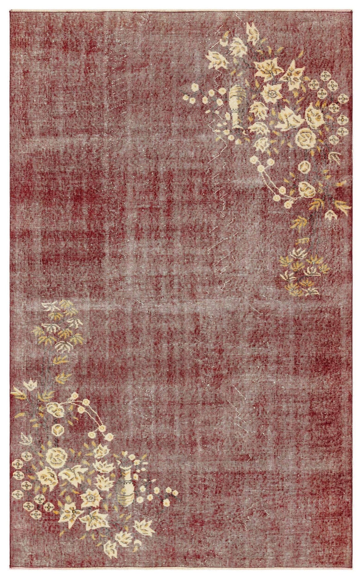 Distressed deep red rug with cream and gold floral corner motifs.