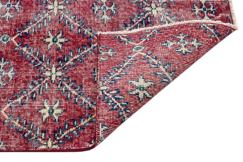 Load image 1 in gallery view. Red rug with a blue and cream floral geometric pattern, shown with a corner folded over to reveal the underside.