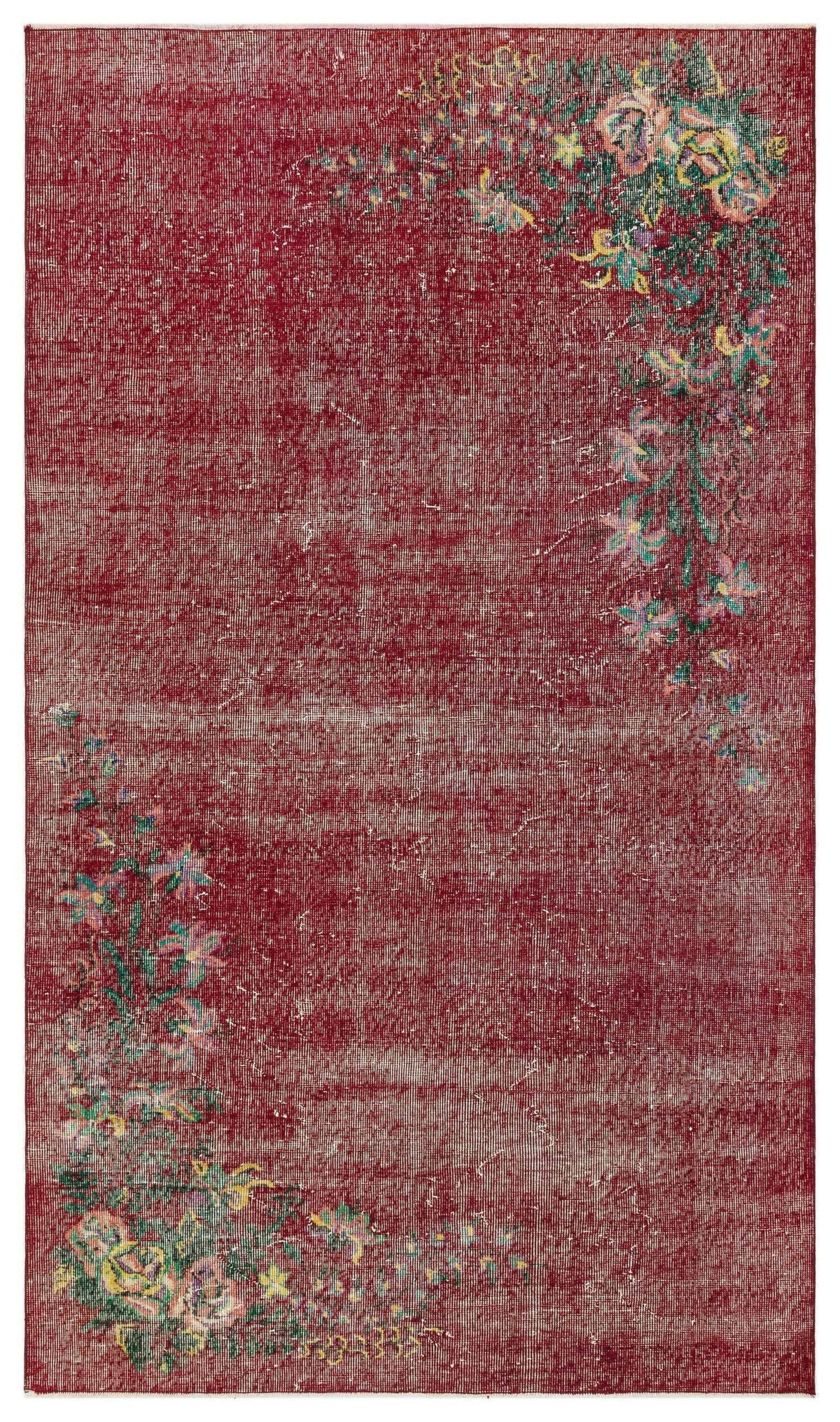 Distressed deep red rug with asymmetrical floral corner motifs in green, yellow, and pink on a white background.