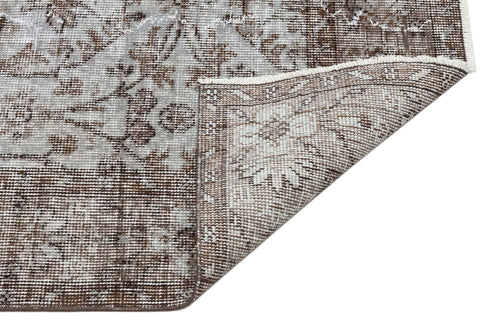 Load image 1 in gallery view. Brown and grey distressed traditional rug with a floral medallion pattern, shown with a corner folded over.
